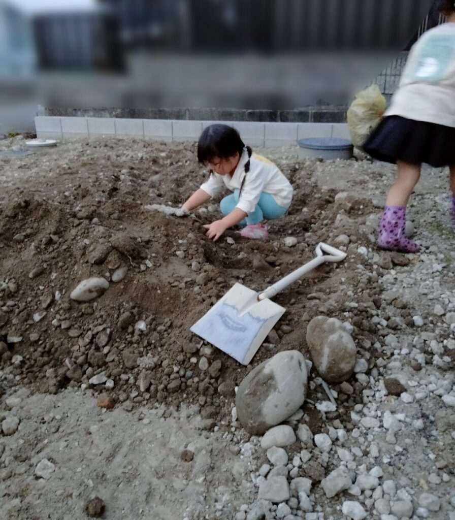 駐車場の整地。残土をユンボで掘り起こすと大きい石が混ざっていた。